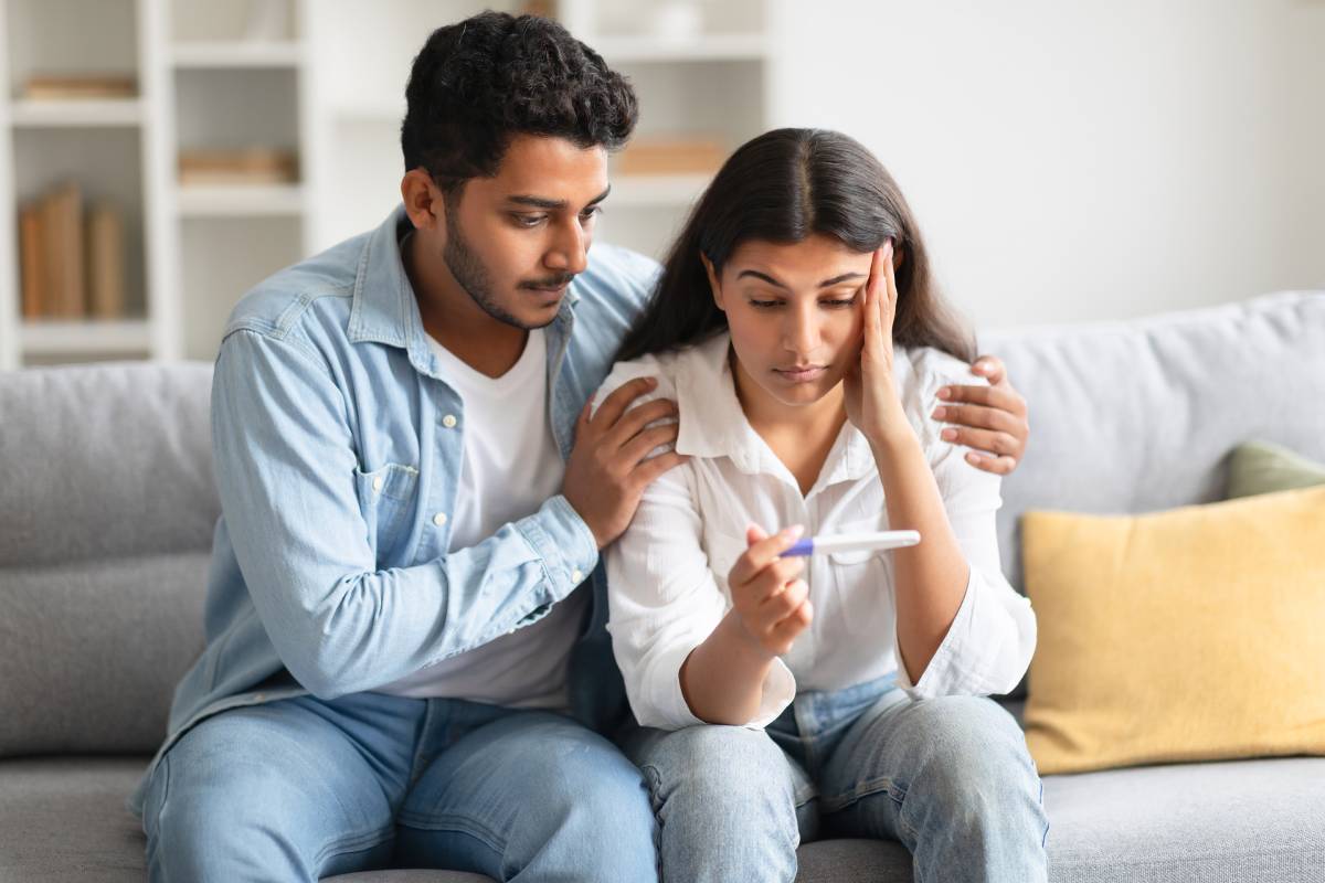unwanted-pregnancy-worried-hindu-couple-looking-positive-test-result-sitting-sofa-home (1)